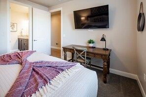 A bedroom with a bed, a desk, a chair, a television, and a small plant. - Paradise Village 51, Private 20x40 Pool & Sport Court (Santa Clara)