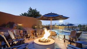An outdoor seating area with Adirondack chairs, a fire pit, and a pool in the background. - Paradise Village 51, Private 20x40 Pool & Sport Court (Santa Clara)