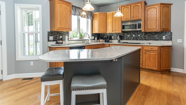 A modern kitchen with wooden cabinets, a granite countertop, a built-in microwave, and pendant lighting. - Private Family Retreat, Pool, Pickleball, 10 acres, 15 Min. from Rochester (Macedon)
