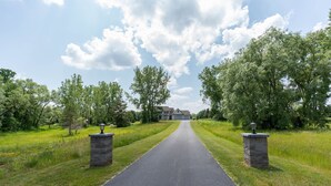 A paved driveway leading to a house with a stone pillar on each side. - Private Family Retreat, Pool, Pickleball, 10 acres, 15 Min. from Rochester (Macedon)