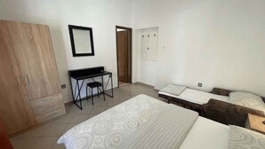 Habitación de hotel con dos camas, un escritorio y un armario.