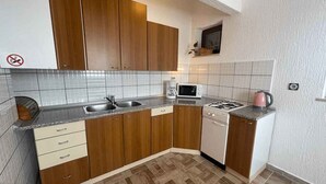 Una cocina compacta con armarios de madera, microondas, estufa a gas y lavavajillas.