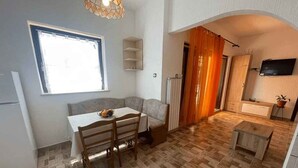 Un espacio habitable compacto con comedor, cocina y una pequeña zona de estar.