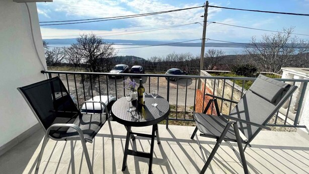 A balcony with a table and chairs, overlooking a scenic view of a body of water and hills. - Holiday apartment with air conditioning and sea views (Dramalj)