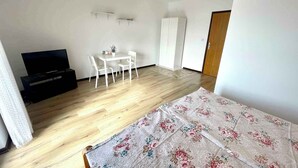 A room with a bed, a TV, a small table with chairs, and a wardrobe. - Holiday apartment with air conditioning and sea views (Dramalj)