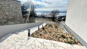 A stone wall, a white building, and a view of the sea. - Holiday apartment with air conditioning and sea views (Dramalj)
