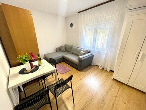 Un espace de vie compact comprenant un coin repas, un canapé et une armoire.
