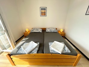 A double bed with two nightstands, each with a lamp, in a room with a large window and a framed picture on the wall.