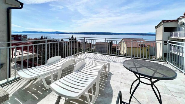 A balcony with white plastic chairs and a metal table, overlooking a body of water and distant hills. - Holiday apartment Spacious with terrace and views (Dramalj)