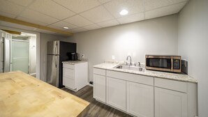Cocina con gabinetes blancos, encimera de granito, refrigerador de acero inoxidable y microondas.
