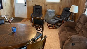 A cozy room with a wooden interior, a round dining table with chairs, a brown sofa, and a ceiling fan. - Inviting lake house in the heart of MN lakes country (Dent)