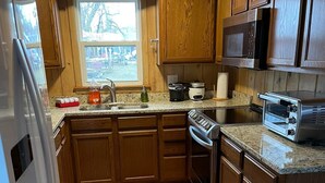 A kitchen with wooden cabinets, a stainless steel refrigerator, a microwave, a toaster, and a sink. - Inviting lake house in the heart of MN lakes country (Dent)