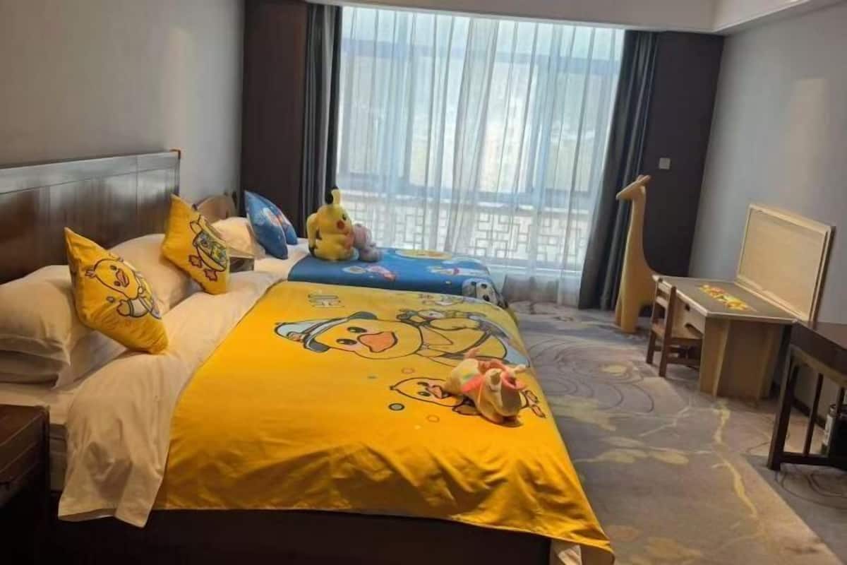 A hotel room with a bed, a desk, and a window with curtains.