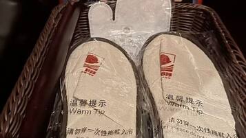 A wicker basket containing two pairs of slippers with a warning label.