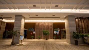 A spacious lobby with a high ceiling, large columns, and potted plants.