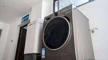 A front-loading washing machine in a room with a door and a window.