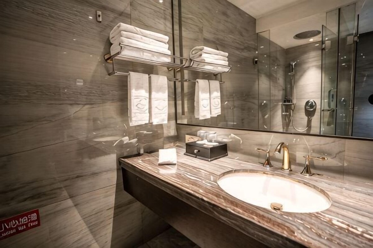 Ein modernes Badezimmer mit Marmorwaschbecken, Handtuchhalter und einem großen Spiegel.