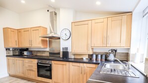 Una cocina moderna con armarios de madera, una campana de acero inoxidable, una encimera negra y un horno empotrado.