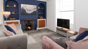 Una sala de estar con chimenea, televisor y un ventanal grande.