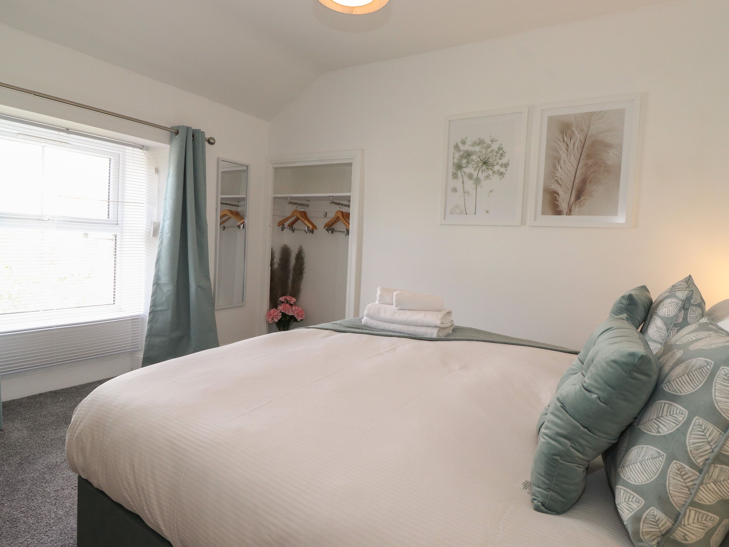 Une chambre avec un grand lit, un dressing et une fenêtre équipée de stores.