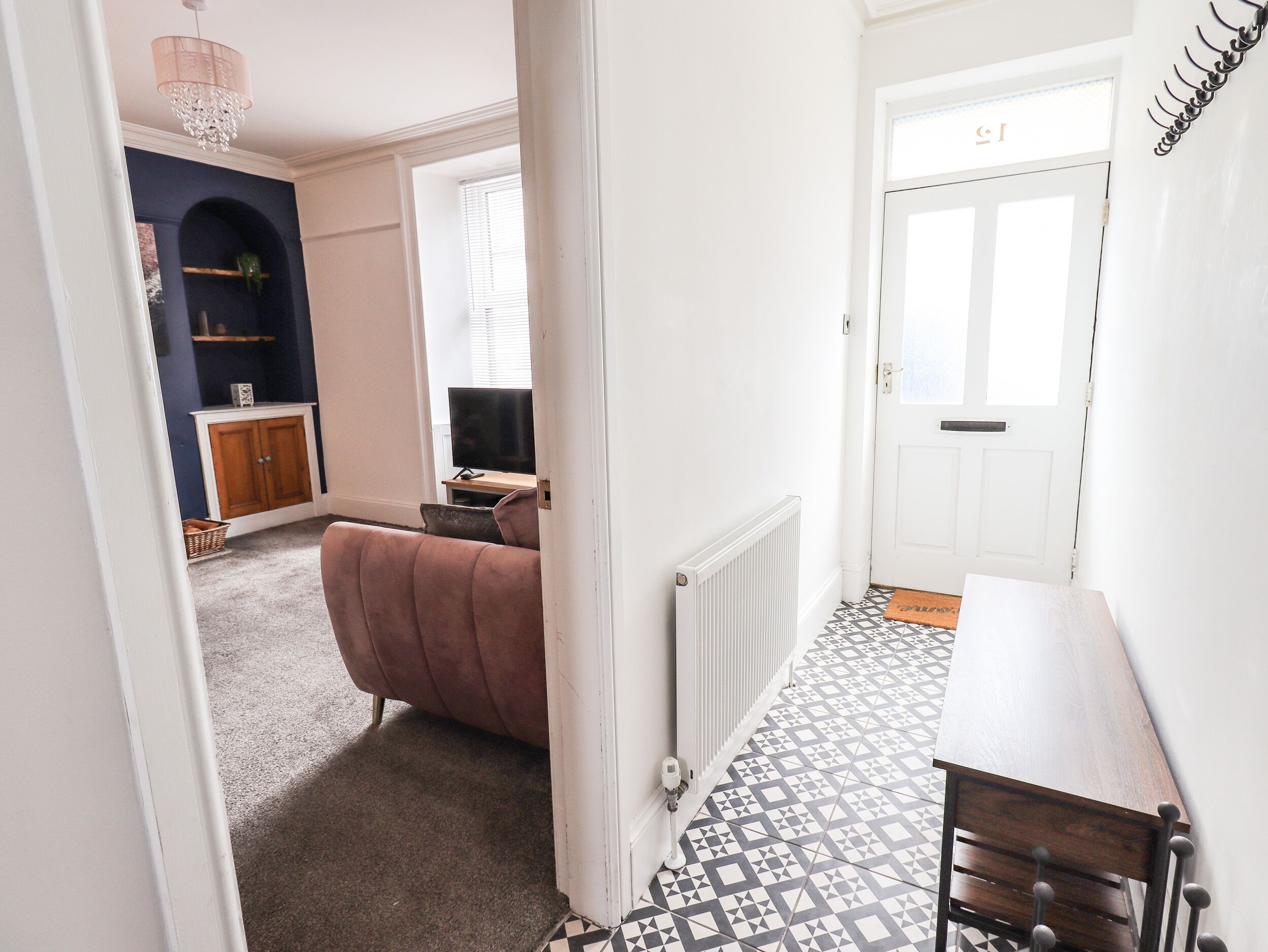 A hallway with a patterned floor, a door labeled "ST", a radiator, and a brown bench.