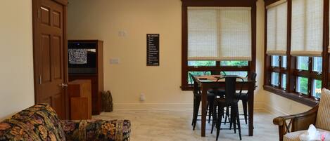 Un comedor con una mesa y sillas de madera, un sofá floral y una ventana con persianas.