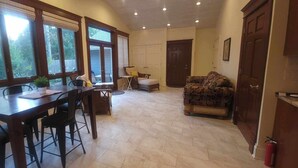 A spacious living area with a dining table, chairs, a sofa, and a kitchen area with cabinets and a countertop. - Welcome! Cozy large house to make memories of laughter and joy by the Big Blue! (South Haven)
