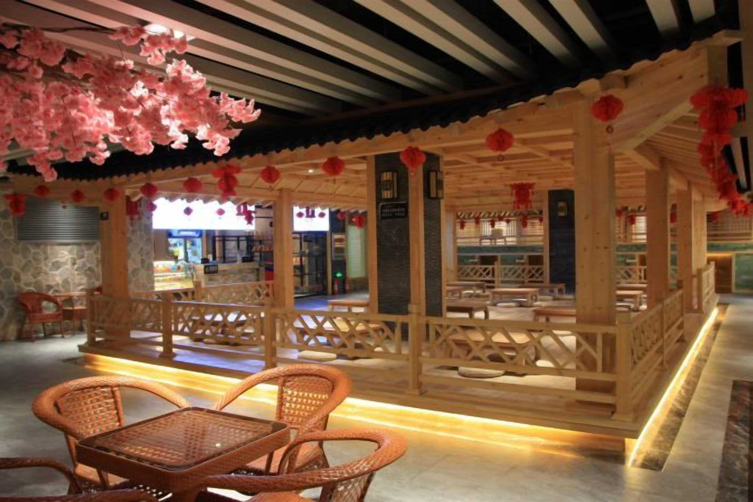 A traditional wooden structure with seating arrangements and a stone wall in the background.