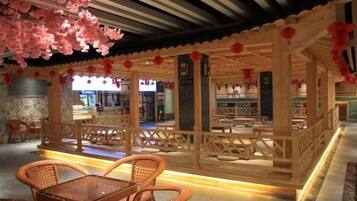 A traditional wooden structure with seating arrangements and a stone wall in the background.