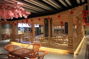 Une structure traditionnelle en bois, avec des sièges disposés à l’intérieur et un mur de pierre en arrière-plan.