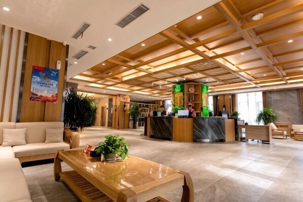 A spacious lobby with a reception desk, seating area, and a large plant.