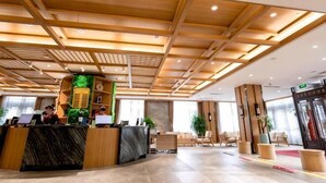 Et hotellets reception med træloft, en receptionsdisk og flere stole.