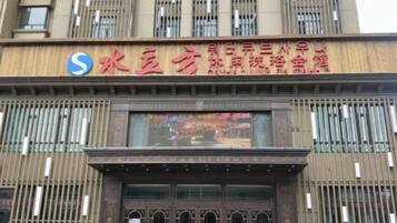 A hotel with a prominent sign featuring Chinese characters and a logo.
