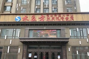 Un hôtel dont l’enseigne est bien visible et qui présente des caractères chinois ainsi qu’un logo.