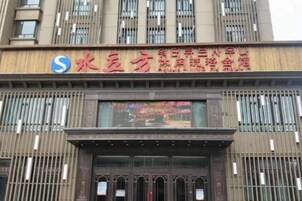 A hotel with a prominent sign featuring Chinese characters and a logo.