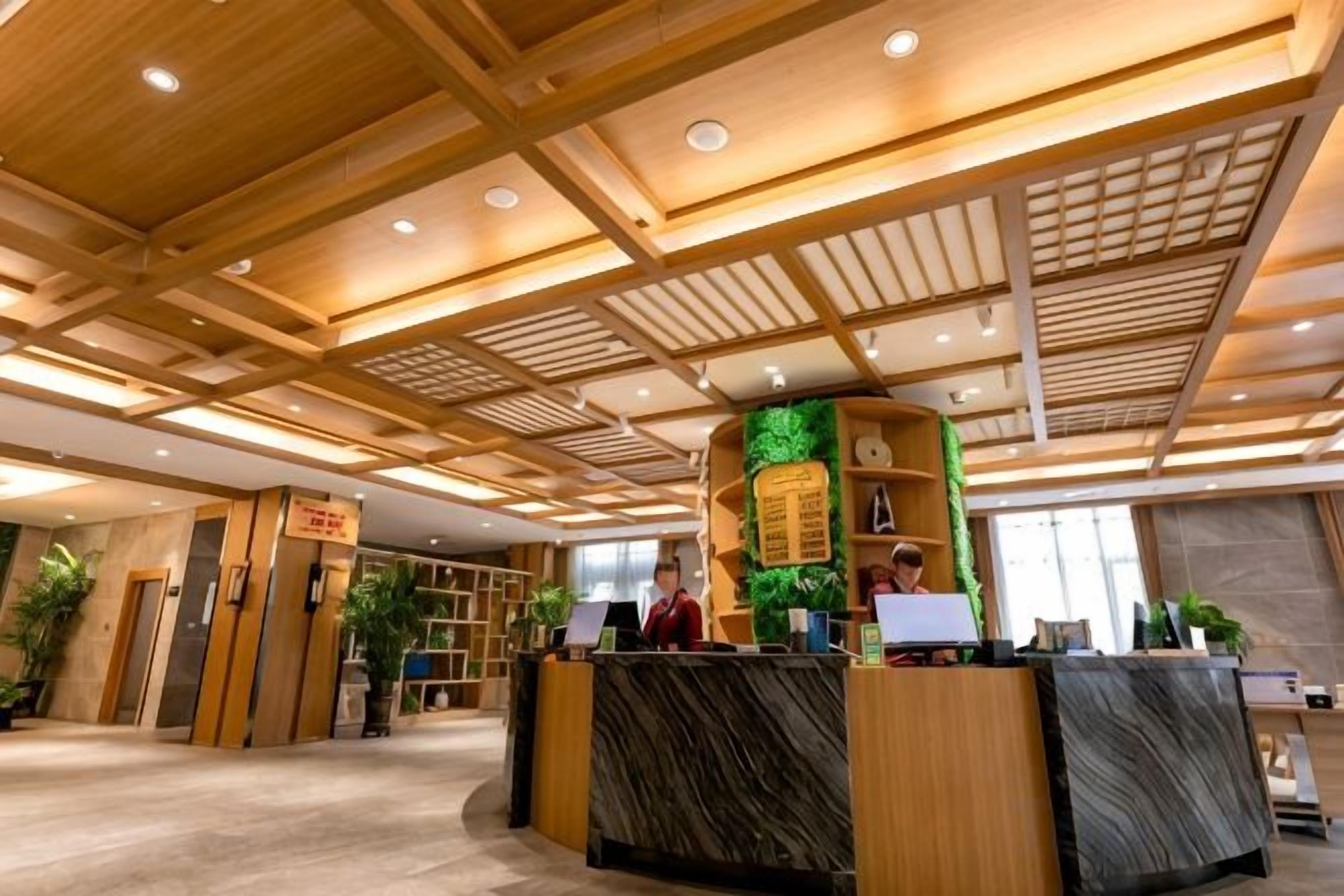 Un comptoir d’accueil avec un revêtement en bois, un jardin vertical verdoyant et une horloge au-dessus.