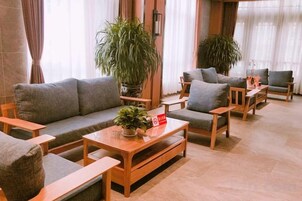 A modern hotel lobby with a sofa set, wooden coffee table, and potted plants.
