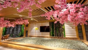 Et traditionelt japansk rum med tatamigulv, en væg dækket af tatami-måtter, træloft og et stort vindue.