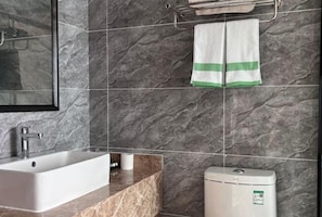 A bathroom with a rectangular sink, a toilet, and a towel rack with a towel.