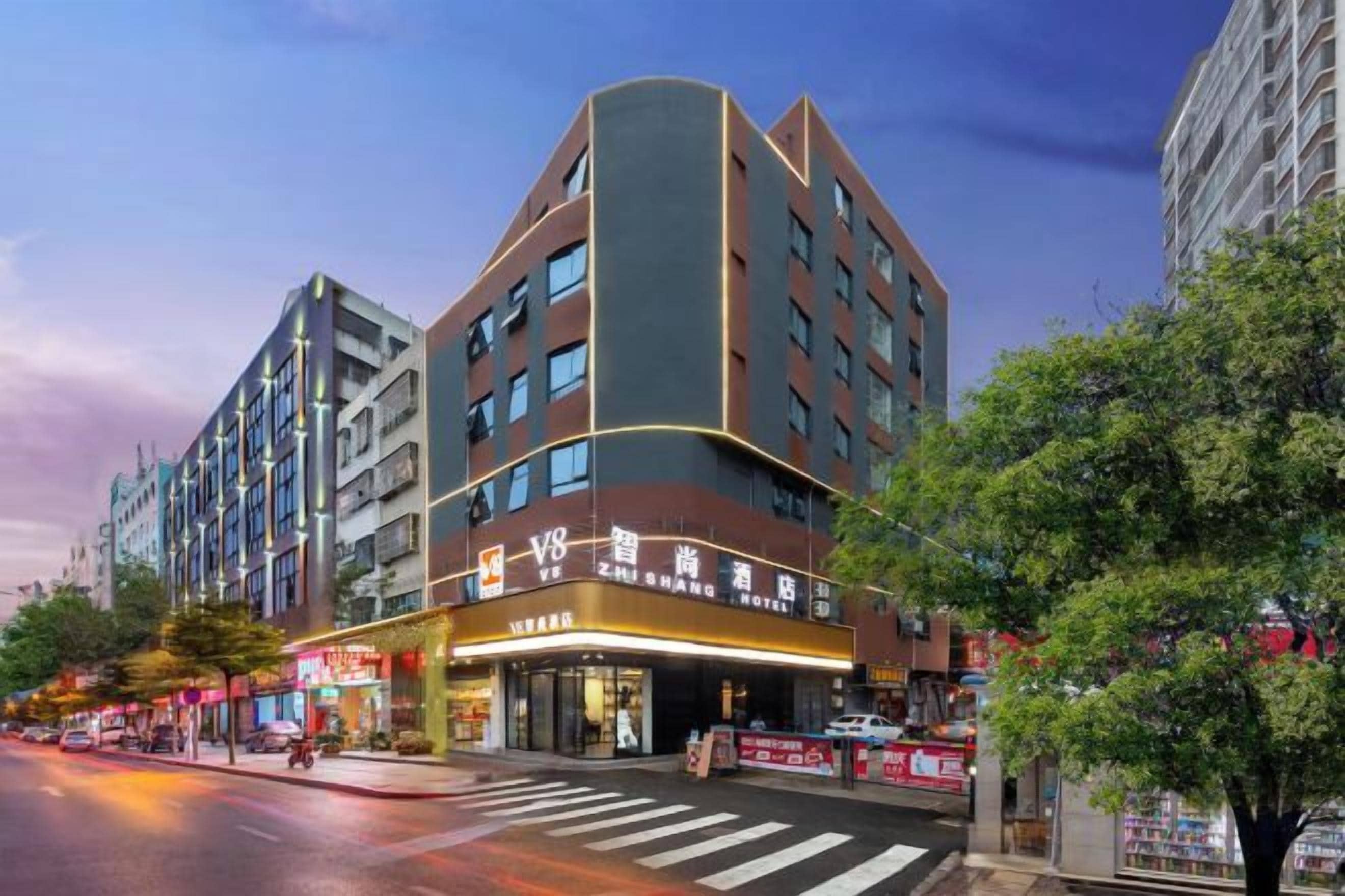 A multi-story hotel with a curved facade, a ground-level restaurant, and a crosswalk in front.