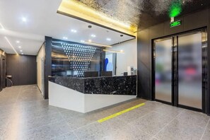 A reception area with a marble counter, a glass wall, and a digital display. - V8 Wisdom Hotel (Haikou CRV East Railway Station) (Haikou)