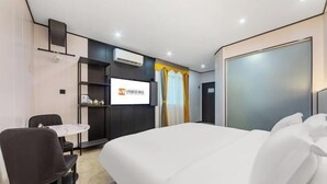 A modern hotel room with a large bed, a desk, and a chair. There is a TV mounted on the wall and a window with curtains. - V8 Wisdom Hotel (Haikou CRV East Railway Station) (Haikou)