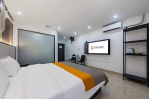 Une chambre d’hôtel équipée d’un lit, d’un bureau, d’une chaise, d’une télévision et d’une étagère avec quelques objets.