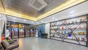 A modern lobby with a glass wall, a statue, a bookshelf, and a seating area. - V8 Wisdom Hotel (Haikou CRV East Railway Station) (Haikou)