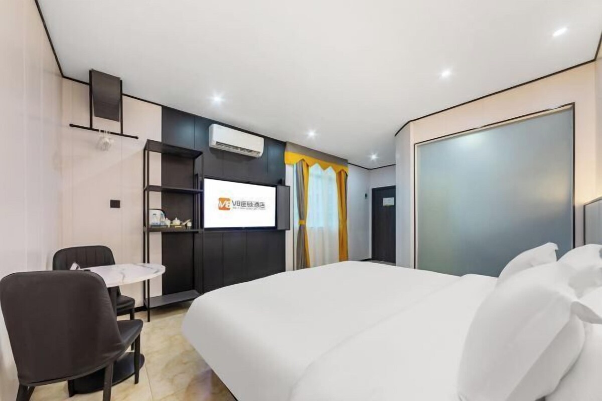 Une chambre d’hôtel moderne équipée d’un grand lit, d’un bureau avec une chaise, d’une télévision et d’une armoire.