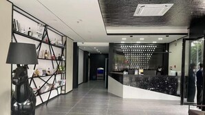 A modern reception area with a black and white color scheme, a reception desk, and a decorative horse sculpture. - V8 Wisdom Hotel (Haikou CRV East Railway Station) (Haikou)