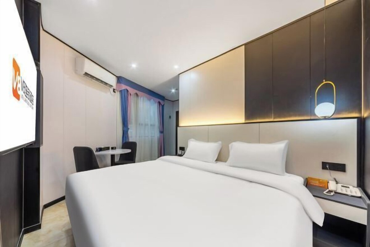 Une chambre d’hôtel comprenant un lit, une table de chevet et un bureau avec une chaise.