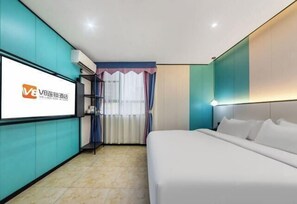 A hotel room with teal walls, a large bed, a TV screen, and a window with curtains. - V8 Wisdom Hotel (Haikou CRV East Railway Station) (Haikou)