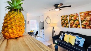 A modern living room with a wooden coffee table, a black sofa with patterned cushions, and a large pineapple centerpiece. - Cozy 2 BR Condo - 7 Min from Fort Lauderdale Beach (Fort Lauderdale)