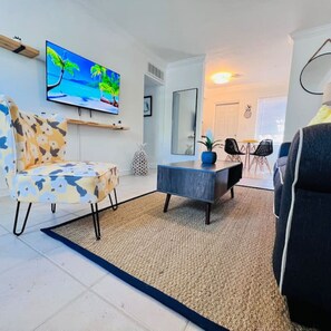 Una sala de estar moderna con un sofá, una mesa de centro y un televisor montado en la pared.